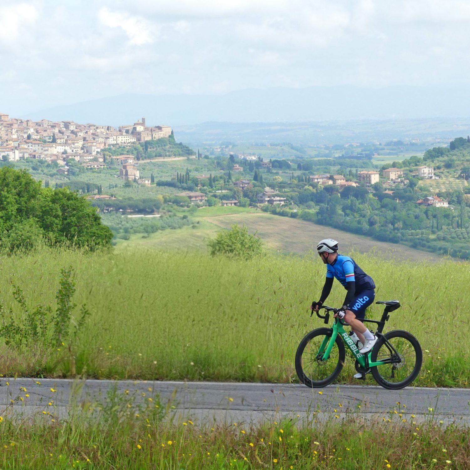 Climbing towards history Solo cyclist climbing a peaceful hill with a hilltop Umbrian town in the distance