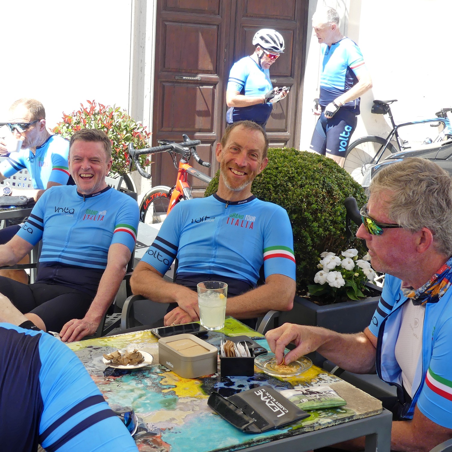 Cyclists relaxing at a shaded café during a coffee break on the Grand Tour Italia: Marche & Abruzzo.