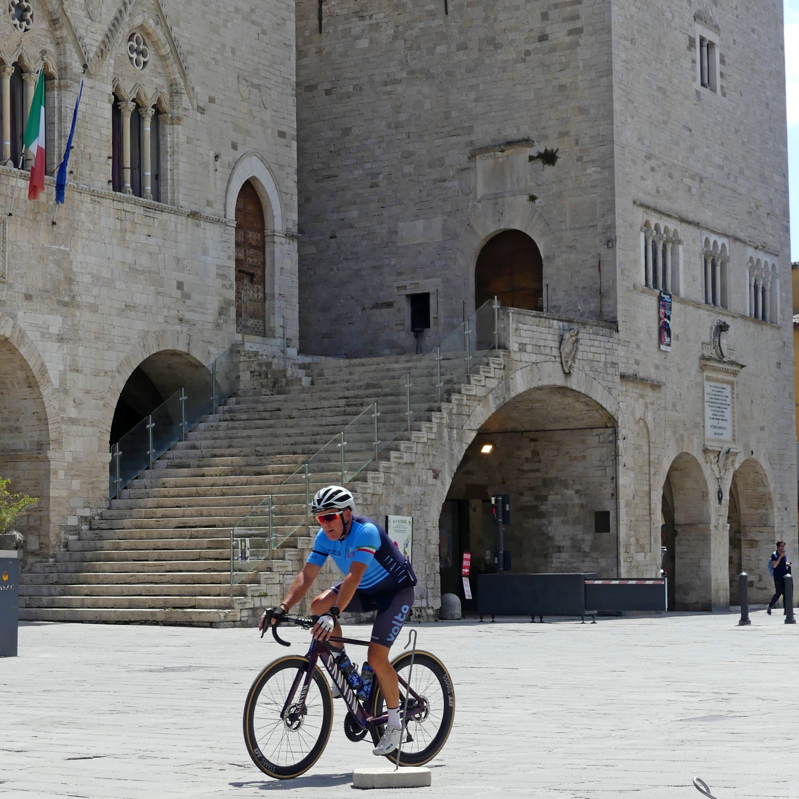 Cycling Through Todi’s Historic Heart Cyclist riding through the medieval piazza of Todi, Umbria
