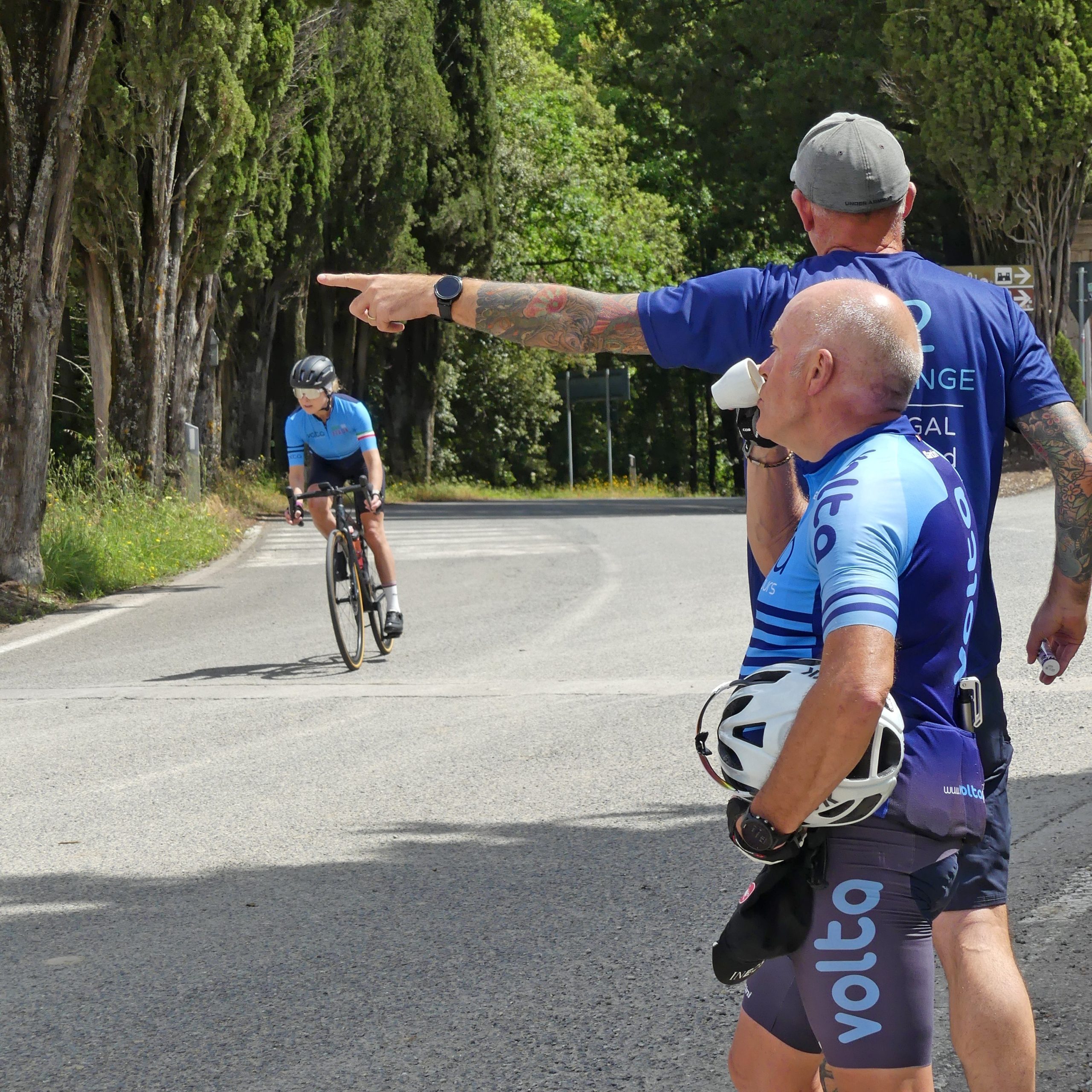 Guidance and Espresso on the Road Ride leader guiding cyclist to café stop while colleague enjoys an espresso